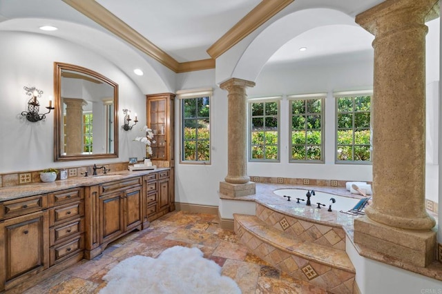 bathroom featuring ornate columns, ornamental molding, a relaxing tiled tub, and vanity