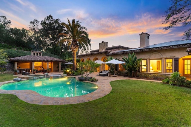 pool at dusk with a patio area, a gazebo, an in ground hot tub, and a lawn