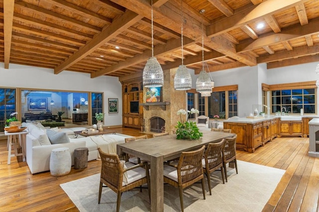 dining area featuring beamed ceiling, wood ceiling, a fireplace, and light hardwood / wood-style floors