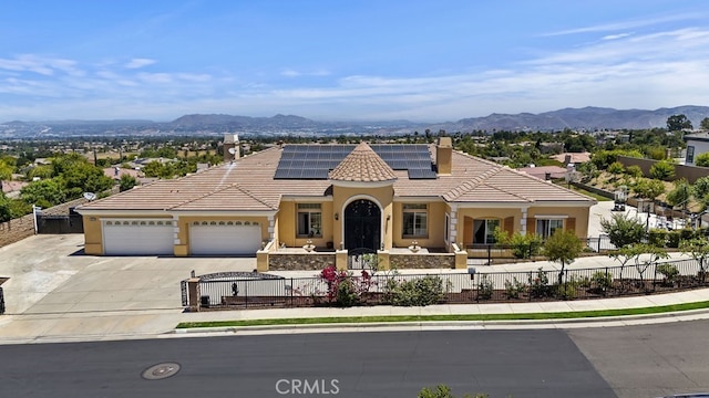 mediterranean / spanish home featuring a mountain view, a garage, and solar panels