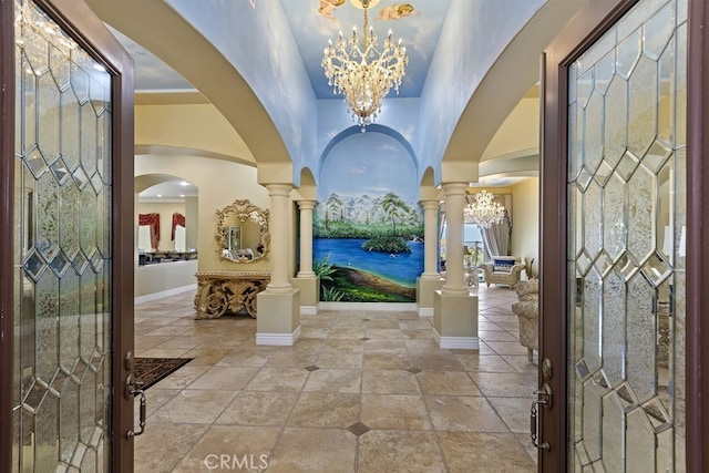 foyer entrance featuring decorative columns and an inviting chandelier