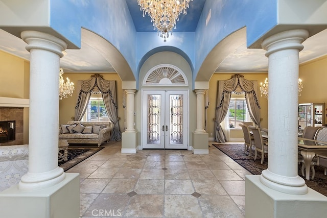 entrance foyer with decorative columns, a chandelier, french doors, and a wealth of natural light