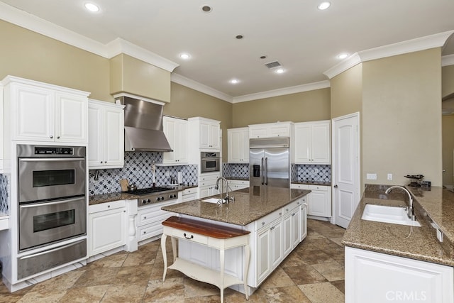 kitchen with dark stone counters, sink, white cabinetry, wall chimney exhaust hood, and stainless steel appliances