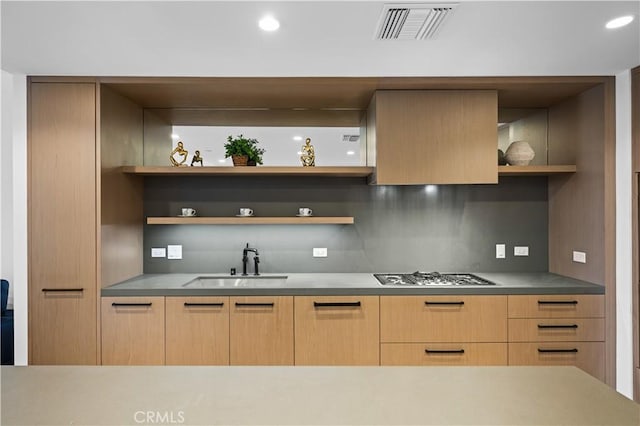 kitchen with decorative backsplash, light brown cabinetry, sink, and stainless steel gas cooktop