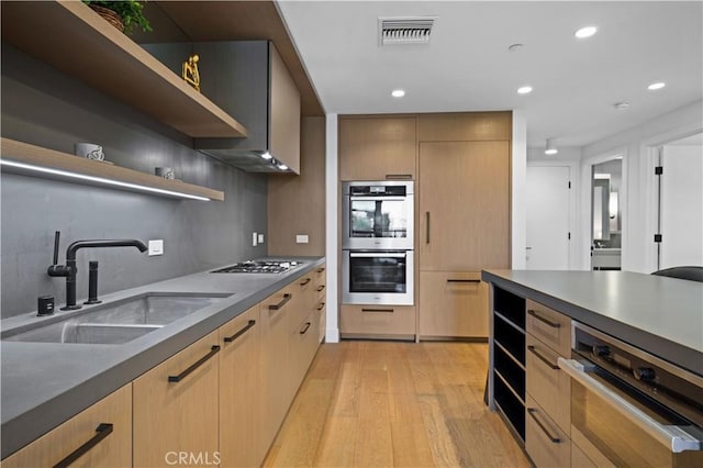 kitchen with light brown cabinetry, sink, appliances with stainless steel finishes, and light hardwood / wood-style flooring