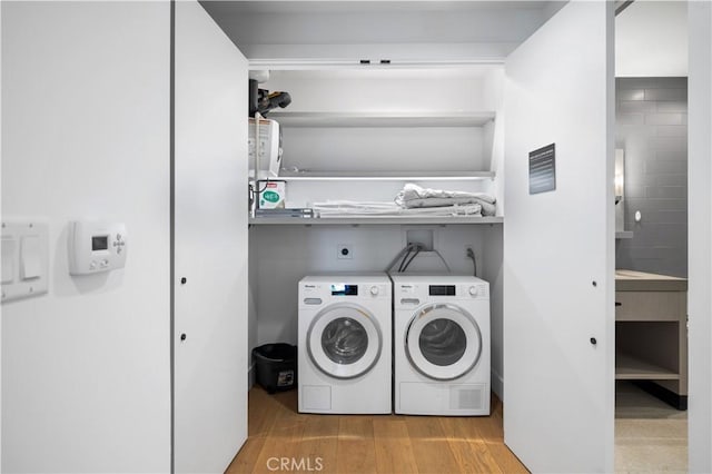 clothes washing area with light hardwood / wood-style flooring and washing machine and clothes dryer