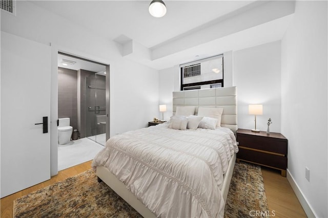 bedroom with ensuite bath and light hardwood / wood-style flooring