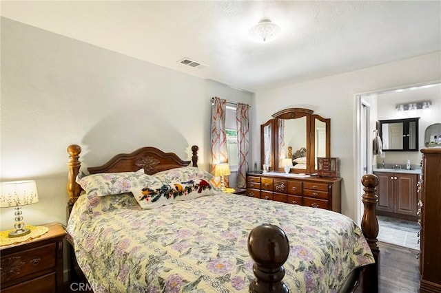 bedroom with ensuite bathroom and dark hardwood / wood-style floors