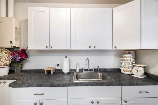 kitchen with white cabinetry, tankless water heater, and sink