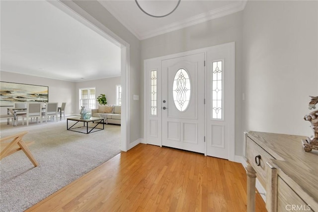 entrance foyer with ornamental molding and light hardwood / wood-style flooring