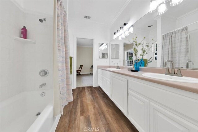 bathroom featuring hardwood / wood-style floors, vanity, ornamental molding, shower / bath combo, and an inviting chandelier