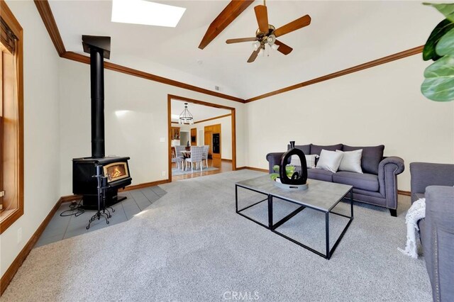 living room featuring light carpet, ceiling fan, a wood stove, and a skylight