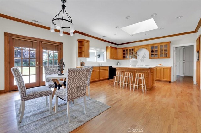 dining space featuring ornamental molding, a skylight, and light wood-type flooring