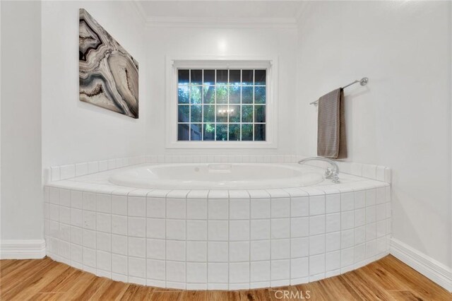 bathroom featuring crown molding, tiled tub, and hardwood / wood-style floors