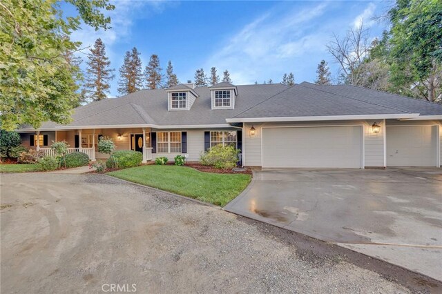 view of front of house with covered porch, a front lawn, and a garage