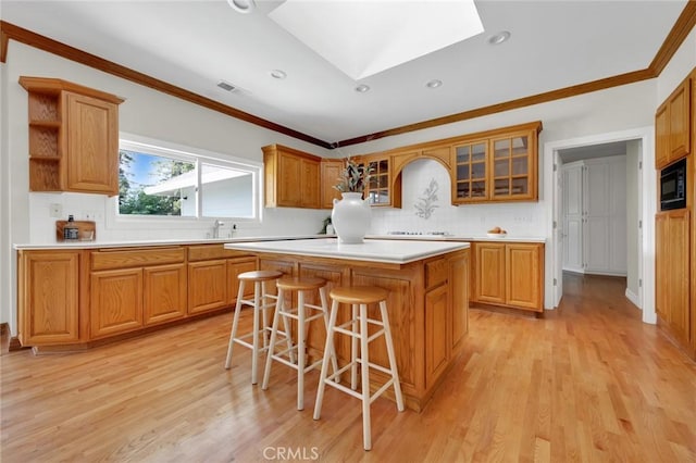 kitchen featuring light hardwood / wood-style flooring, a center island, a breakfast bar, a skylight, and black microwave