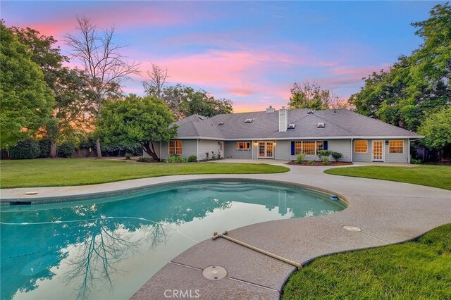 pool at dusk featuring a yard and a patio area