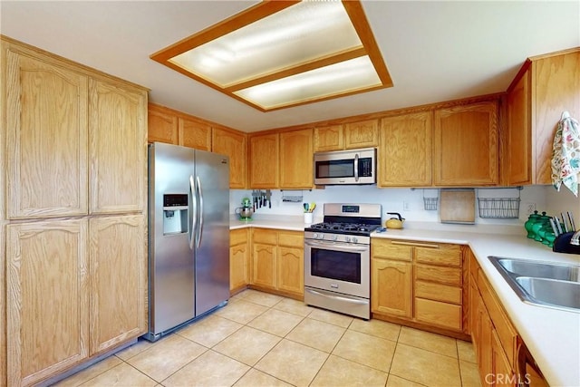 kitchen with appliances with stainless steel finishes, light tile patterned floors, and sink