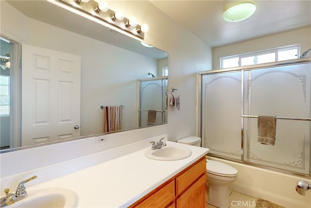 full bathroom featuring tile patterned flooring, vanity, toilet, and bath / shower combo with glass door