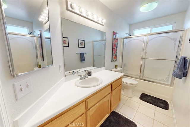 full bathroom featuring combined bath / shower with glass door, tile patterned floors, vanity, and toilet