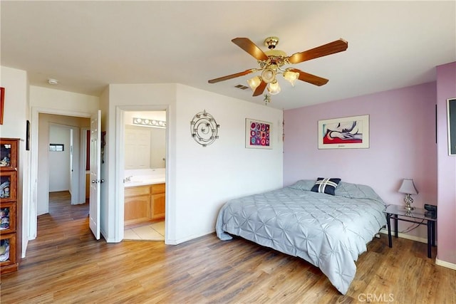 bedroom with ceiling fan, connected bathroom, and light hardwood / wood-style flooring