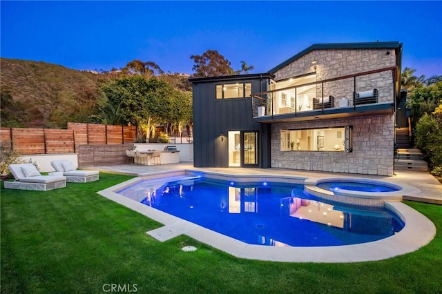 pool at dusk with a lawn and an in ground hot tub