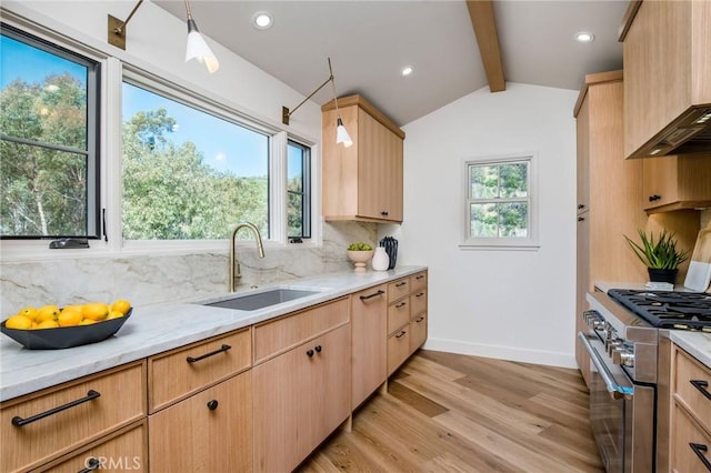 kitchen with light hardwood / wood-style floors, sink, hanging light fixtures, and high end stainless steel range