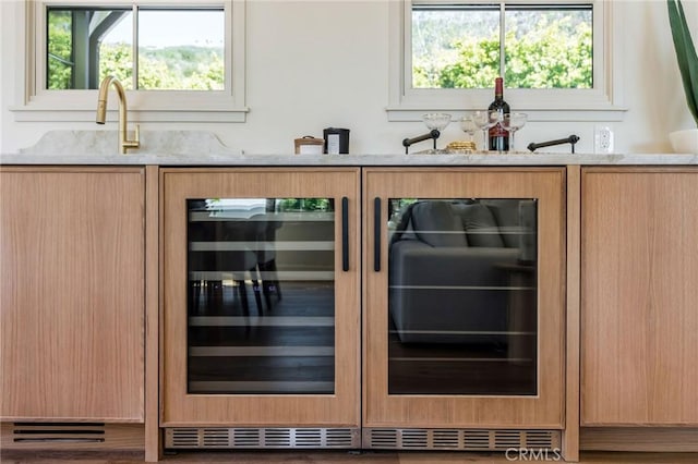 bar with light brown cabinetry and beverage cooler