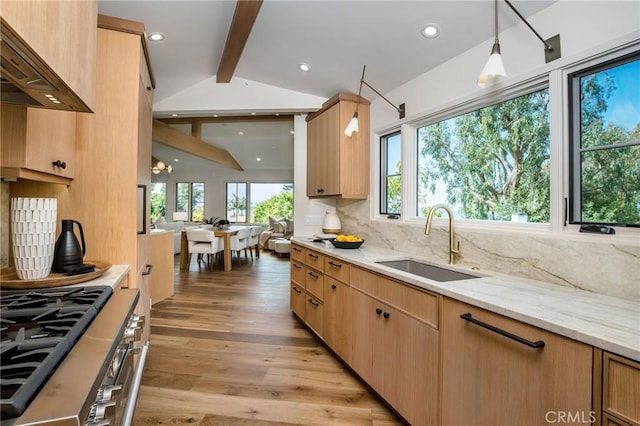 kitchen with sink, lofted ceiling with beams, high end stove, light hardwood / wood-style floors, and decorative light fixtures