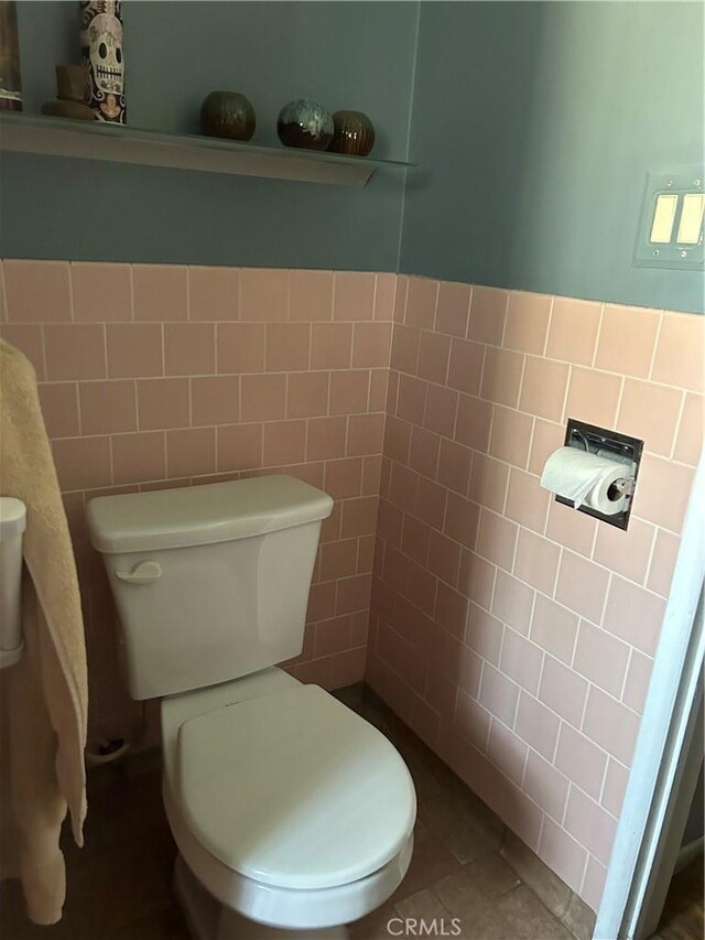 bathroom with tile patterned floors, toilet, and tile walls