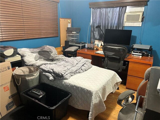 bedroom with an AC wall unit and light hardwood / wood-style floors