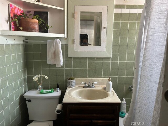 bathroom with vanity, toilet, and tile walls