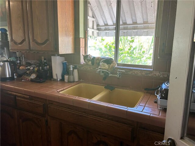 kitchen featuring tile countertops, backsplash, and sink