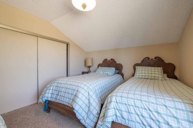 carpeted bedroom with lofted ceiling, a textured ceiling, and a closet