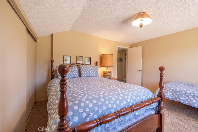 carpeted bedroom with a textured ceiling, vaulted ceiling, and a closet