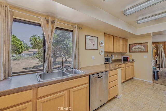 kitchen with light brown cabinetry, stainless steel dishwasher, and sink