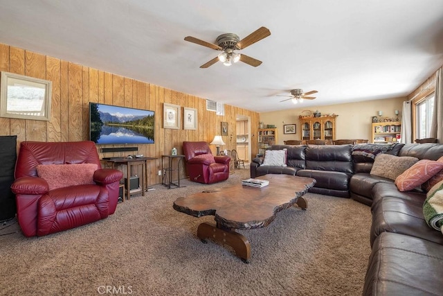 carpeted living room featuring ceiling fan and wood walls