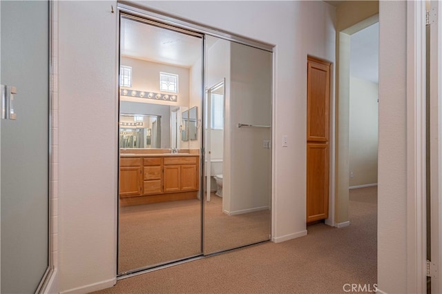 carpeted bedroom with ensuite bath and a closet