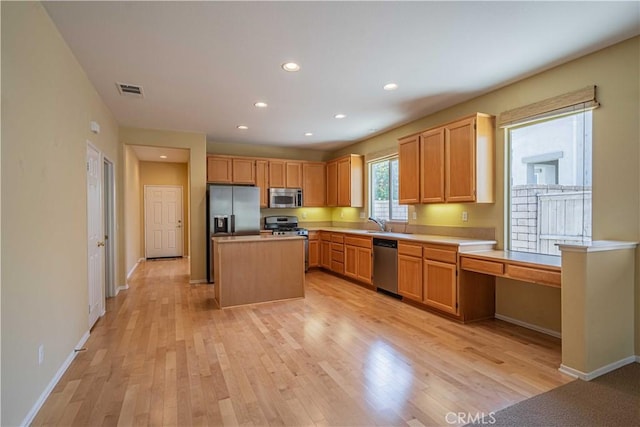 kitchen featuring sink, light hardwood / wood-style flooring, appliances with stainless steel finishes, a kitchen island, and light brown cabinets