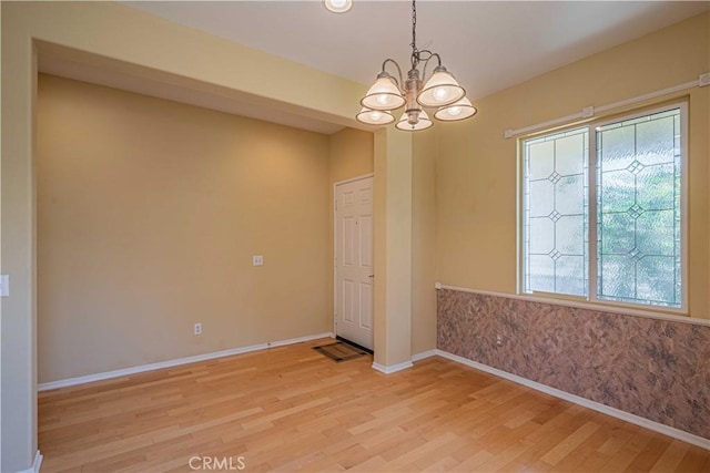 spare room featuring an inviting chandelier and light hardwood / wood-style floors