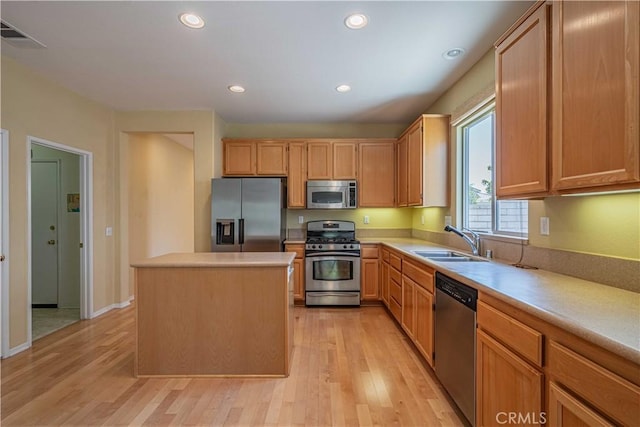 kitchen with sink, a center island, light brown cabinets, stainless steel appliances, and light hardwood / wood-style floors