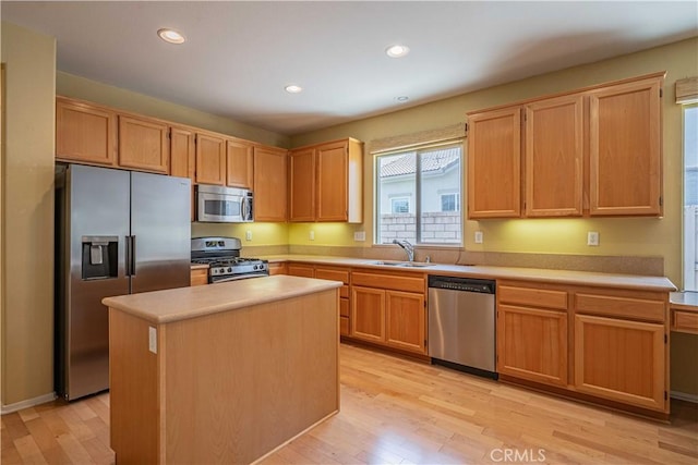 kitchen with appliances with stainless steel finishes, a center island, sink, and light hardwood / wood-style flooring