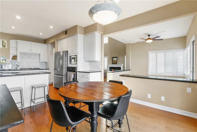 dining room featuring ceiling fan, a healthy amount of sunlight, and light wood-type flooring