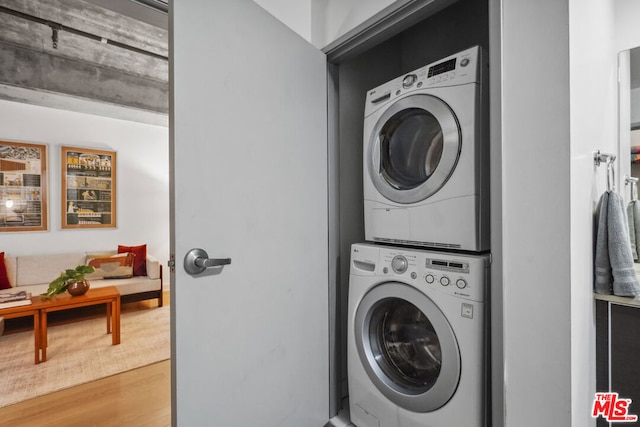 washroom with stacked washer and dryer and hardwood / wood-style flooring