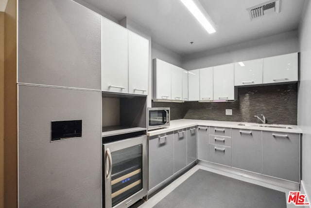 kitchen featuring white cabinetry, sink, wine cooler, and tasteful backsplash