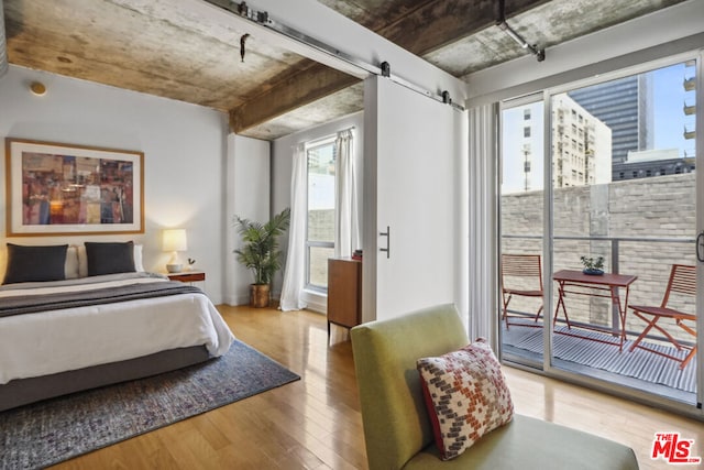 bedroom with hardwood / wood-style floors, a barn door, and access to outside