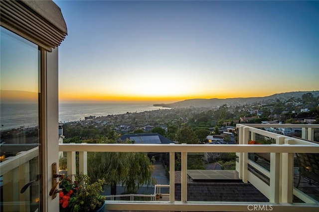 balcony at dusk featuring a water view