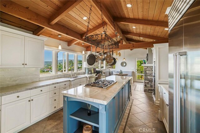 kitchen with lofted ceiling with beams, white cabinets, stainless steel appliances, and a kitchen island