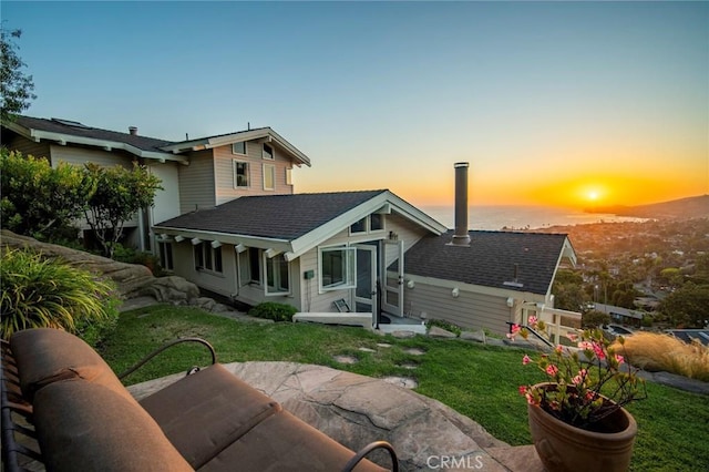 back house at dusk with a yard and a patio area