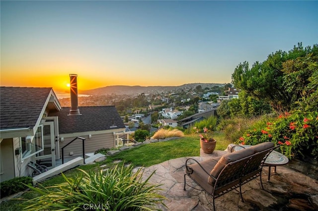 patio terrace at dusk featuring a yard and a mountain view